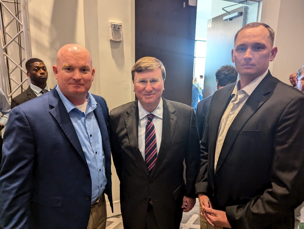 Michael McGill and Zac Christianson take a photo with Governor Tate Reeves at the 2024 Policy and Tax Reform in Jackson Mississippi