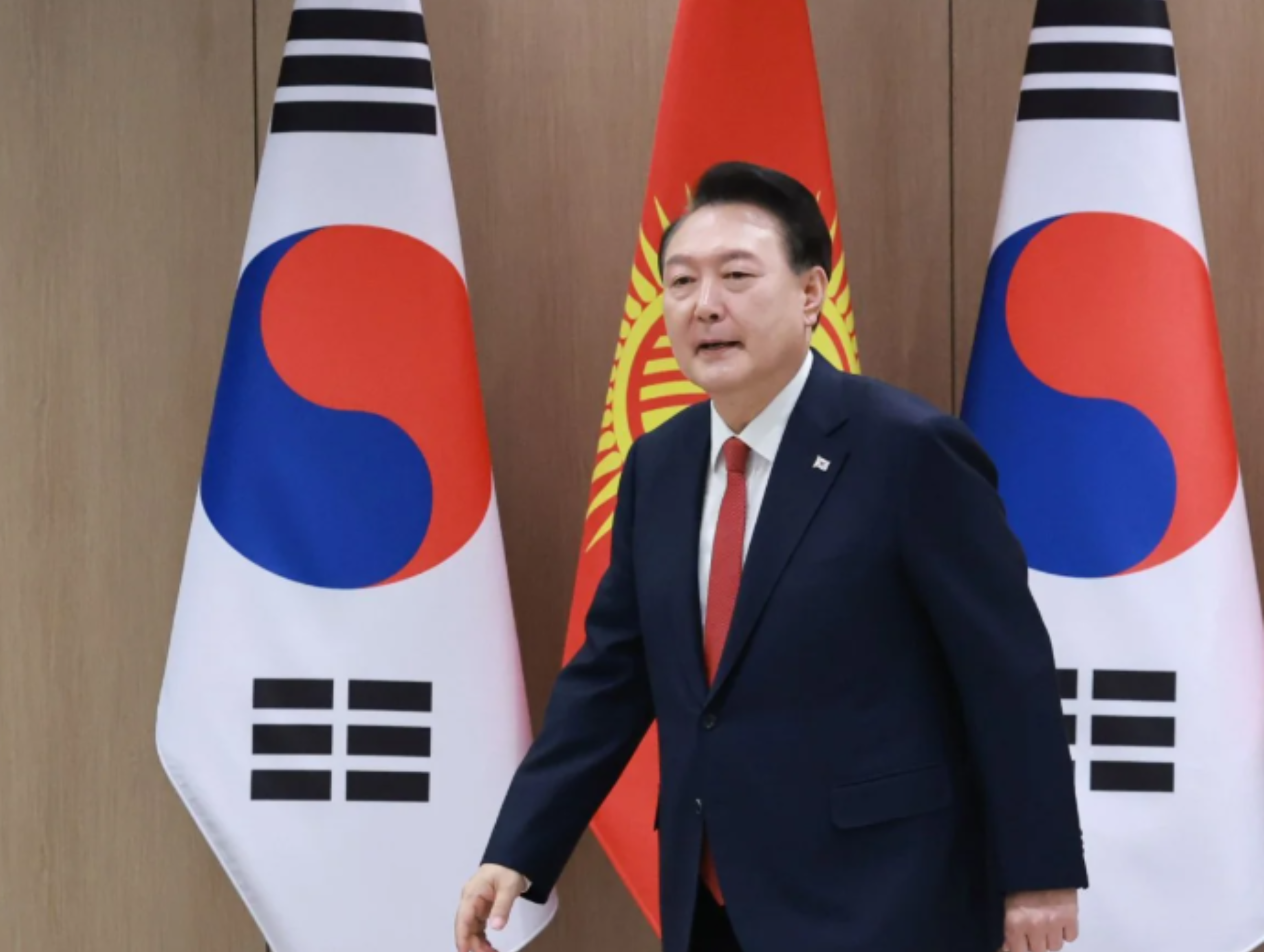 President Yoon walking front of two South Korean flags to get a statement on TV about South Korean Martial Law