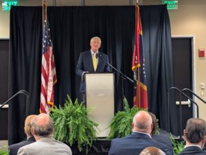 PXL_20250805_172410186 Senator Roger Wicker speaks from a podium at the Gulfport Chamber of Commerce’s 2025 Legislative Luncheon, held at Mississippi Gulf Coast Community College’s Hospitality Resort Management Center. Flanked by American and Mississippi state flags, Wicker addresses an audience of civic and business leaders seated before him.