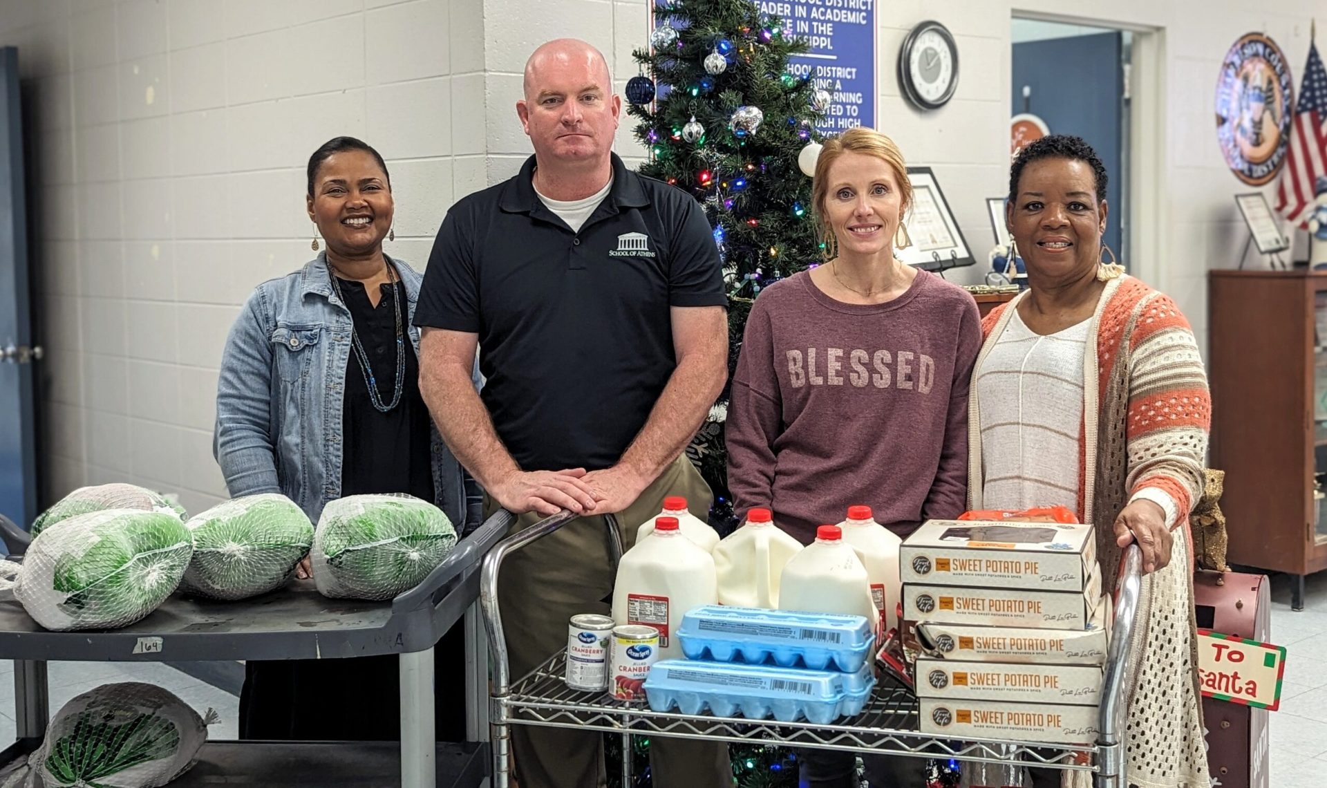 Michael McGill with three school staff members and carts of Thanksgiving turkeys, milk, eggs and sweet potato pies for students' families