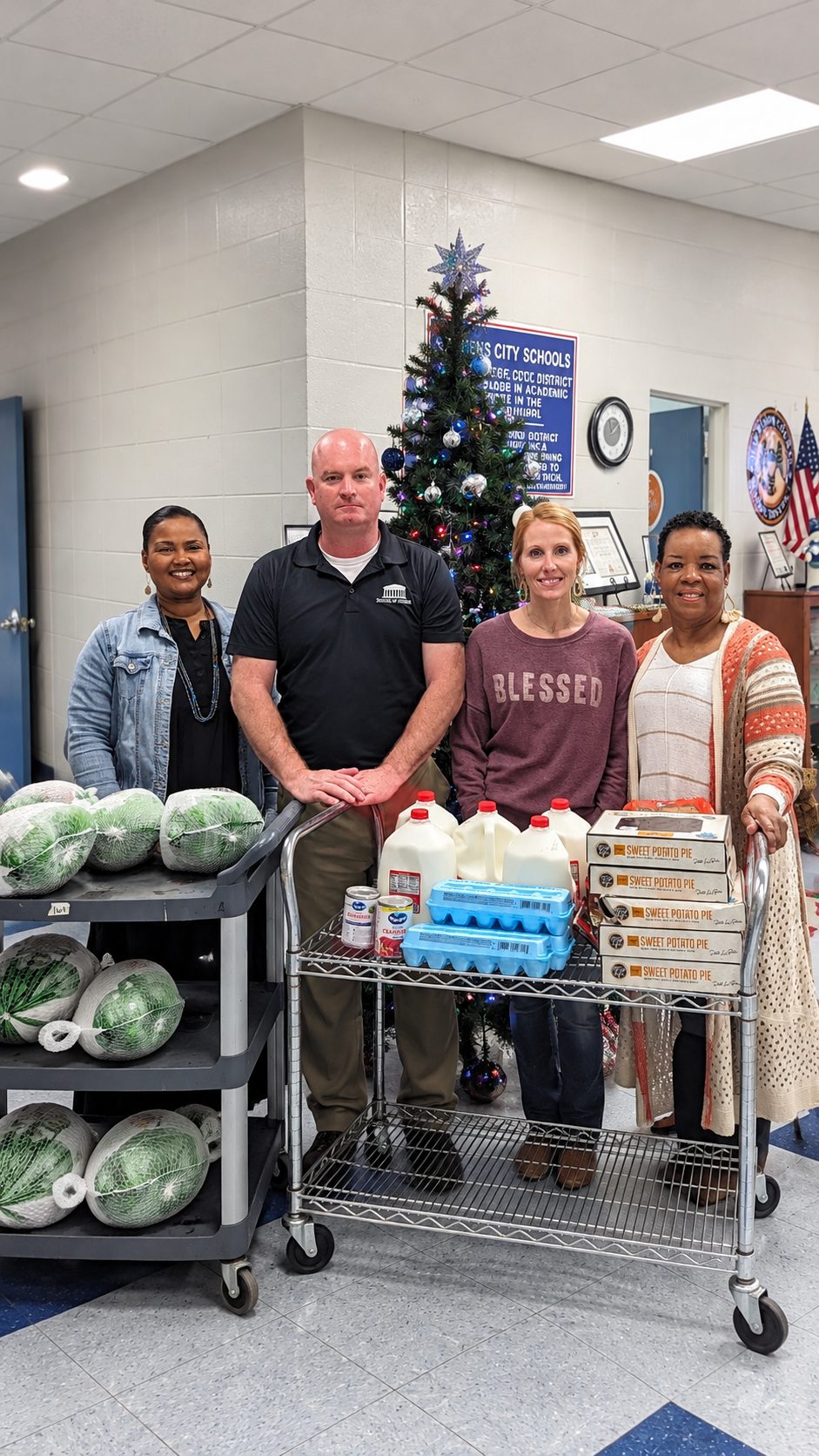 Michael McGill with three school staff members and carts of Thanksgiving turkeys, milk, eggs and sweet potato pies for students' families