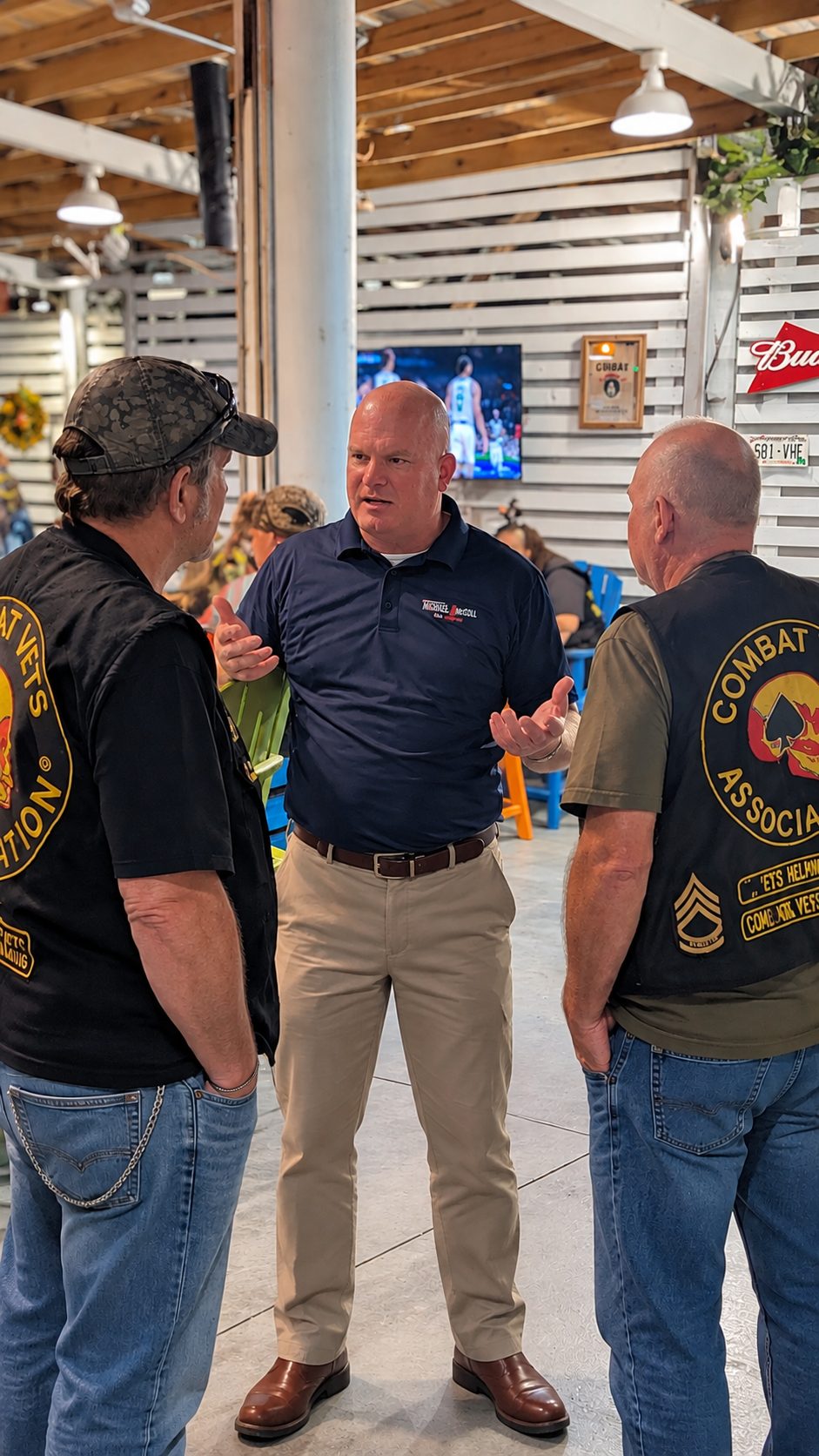 Michael McGill talks with two veterans wearing motorcycle club vests at a community gathering in Mississippi